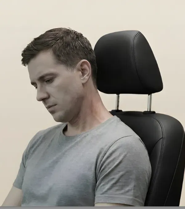 A man with his head slumped forward in a seat